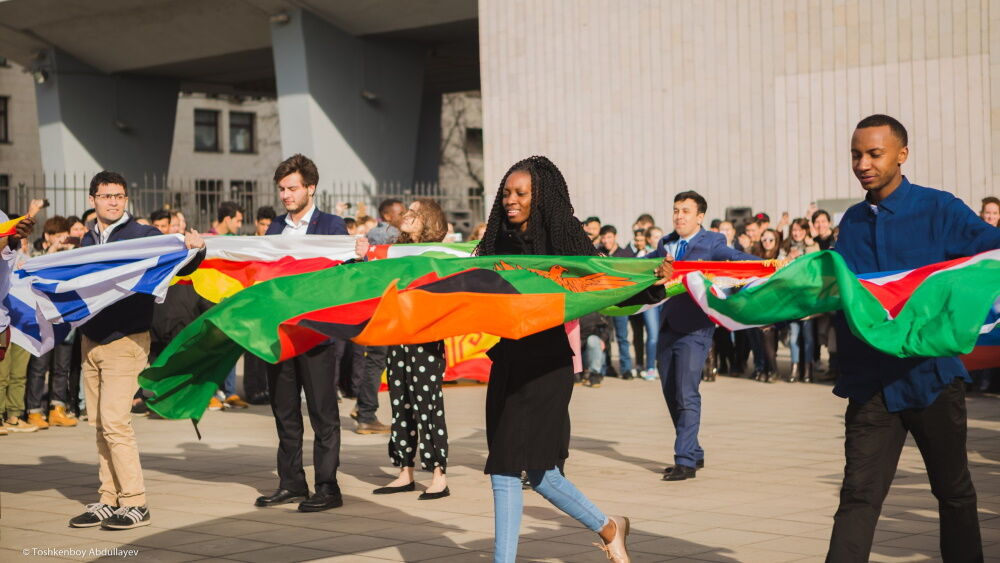 Фотография студентов, танцующих с флагами во время Дня национальностей